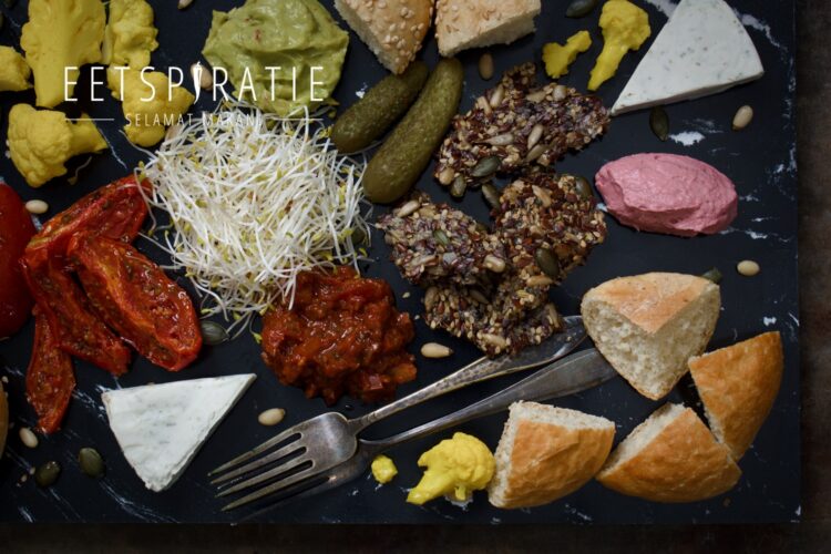 Borrelplank met stukjes brood, tapenade, hummus, guacamole, ingelegde groenten en zadencrackers
