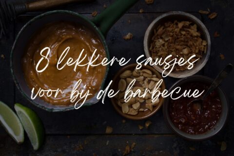 Een aantal schaaltjes met pindasaus, gebakken uitjes, sambal en pinda's ter illustratie en de tekst op de foto: 8 lekkere sausjes voor bij de barbecue