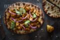 Een platbrood met kip kerrie, komkommer en rode ui