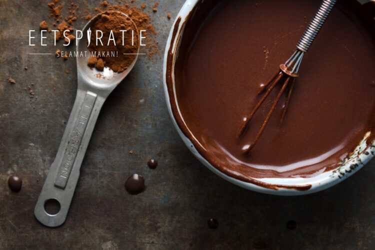 Een schaaltje chocoladesaus en een theelepel cacaopoeder ernaast