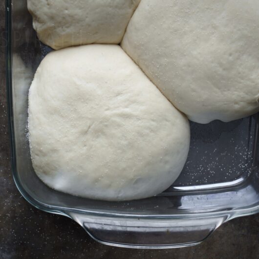 Een ovenschaal met drie bollen pizzadeeg