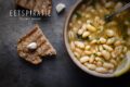 Een bord met bonen in bouillon, ook wel brothy beans genoemd. Geserveerd met knoflooktoast en citroen.