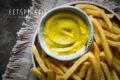 Een bord friet met een schaaltje gele McDonalds fritessaus