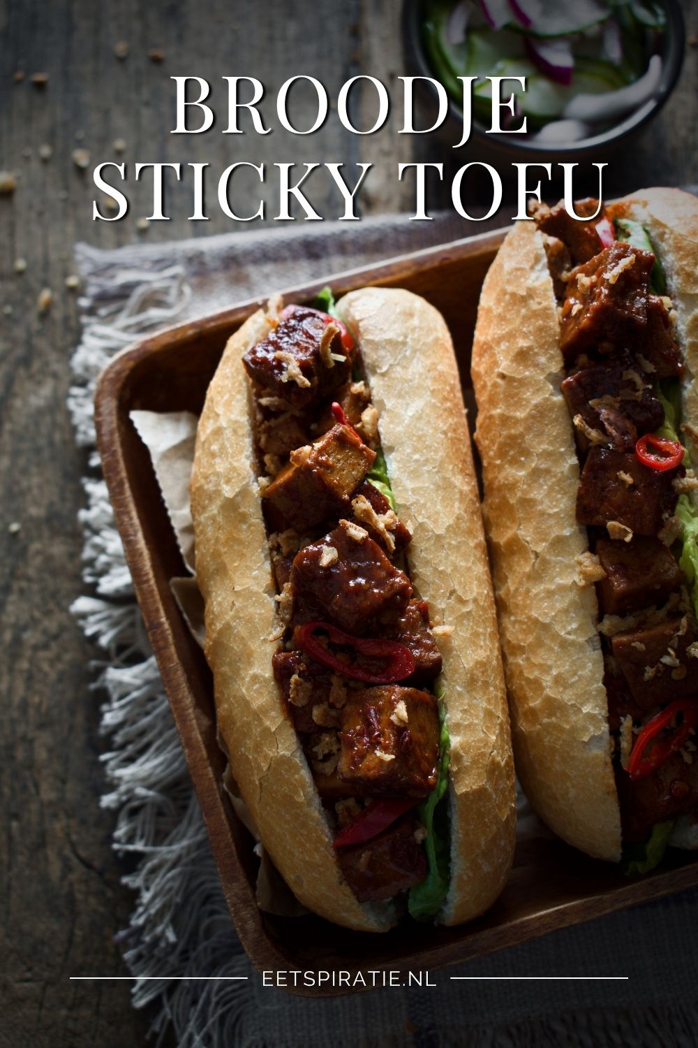 Twee broodjes met pittige tofu, met sla, rode peper en gebakken uitjes. Tekst op de foto: Broodje sticky tofu